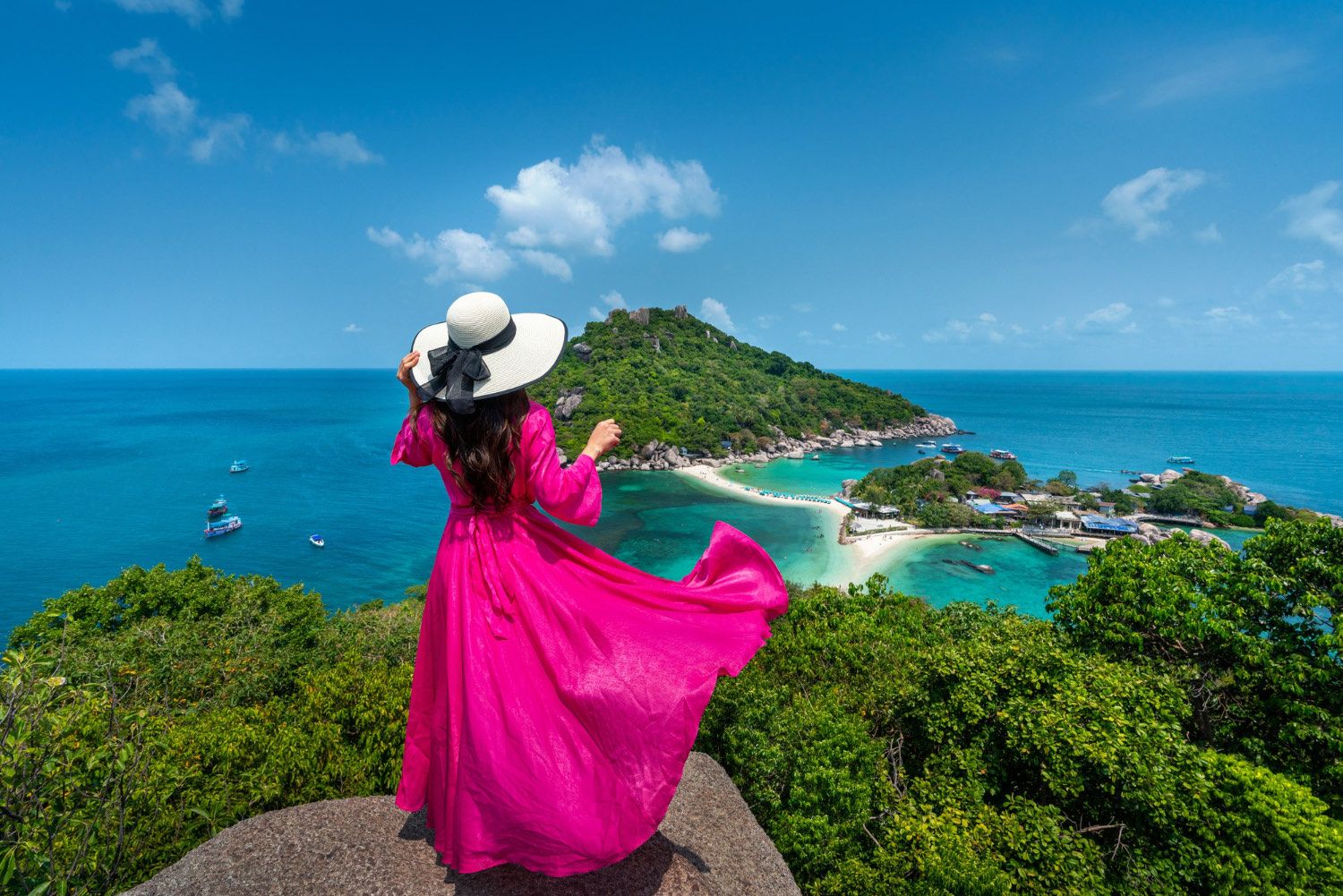 Traveller in a flowing dress overlooking a turquoise island bay