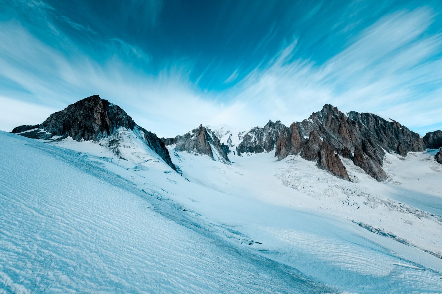 Dramatic snow-capped mountain range under a bright sky